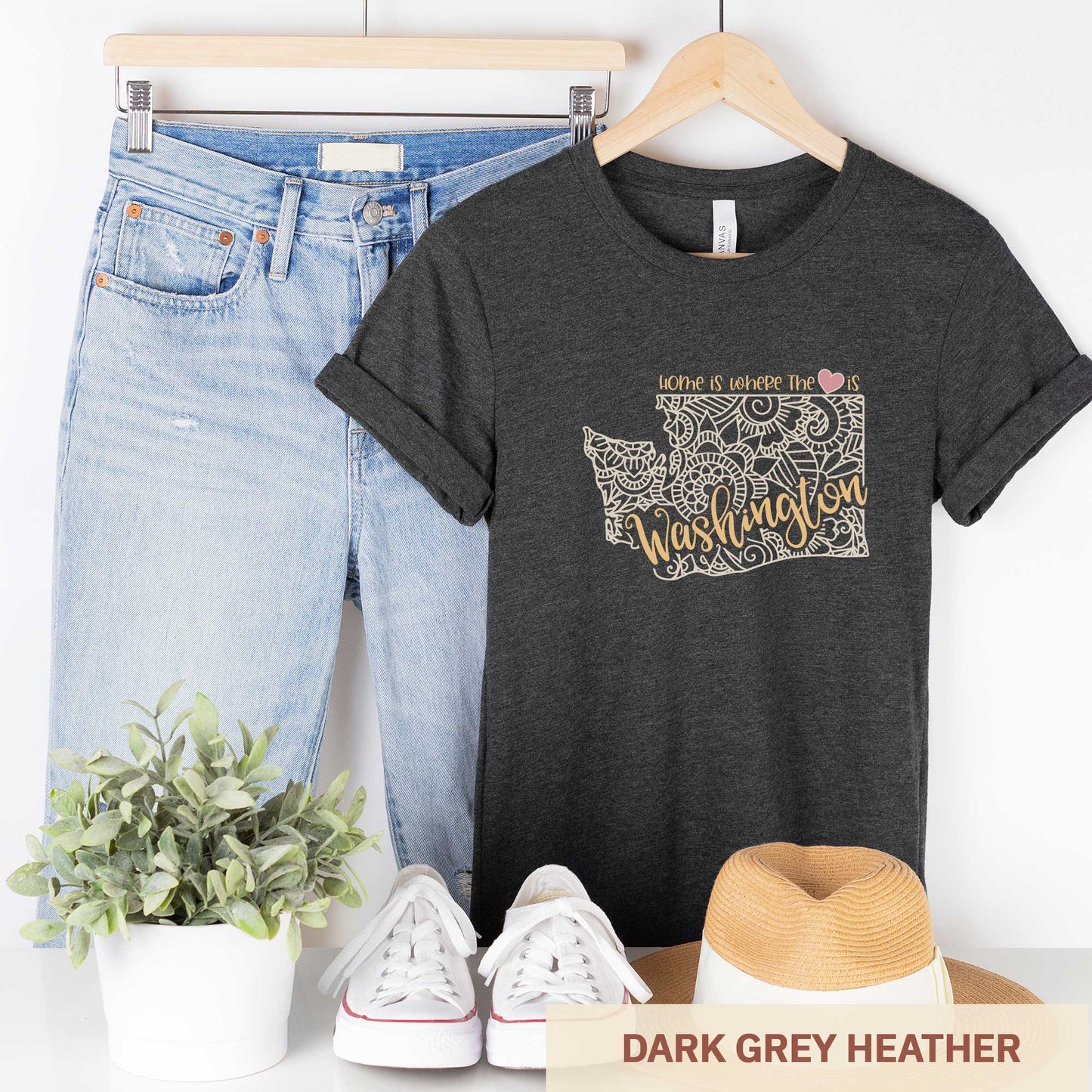 A hanging dark grey heather Bella Canvas t-shirt featuring a mandala in the shape of Washington with the words home is where the heart is.