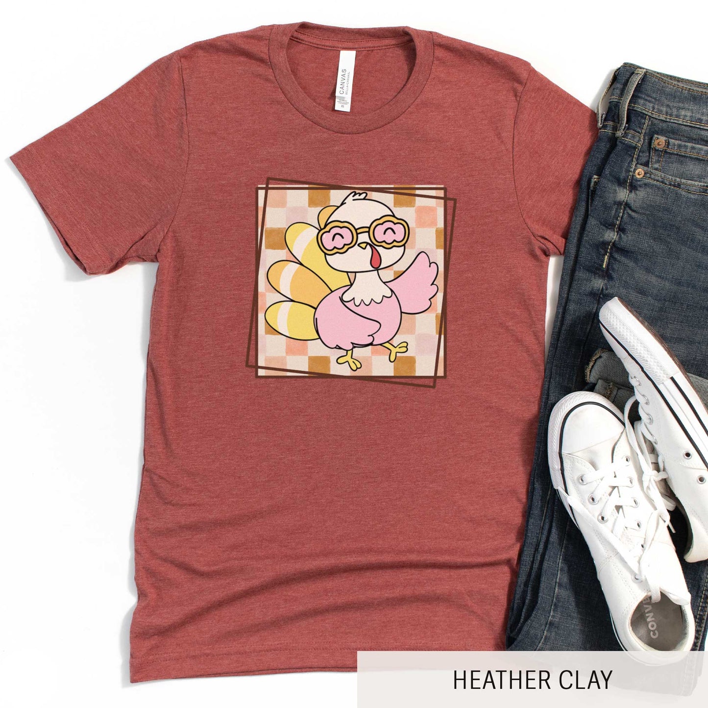A heather clay Bella Canvas t-shirt featuring a cute cartoon turkey against a fall checkered background.