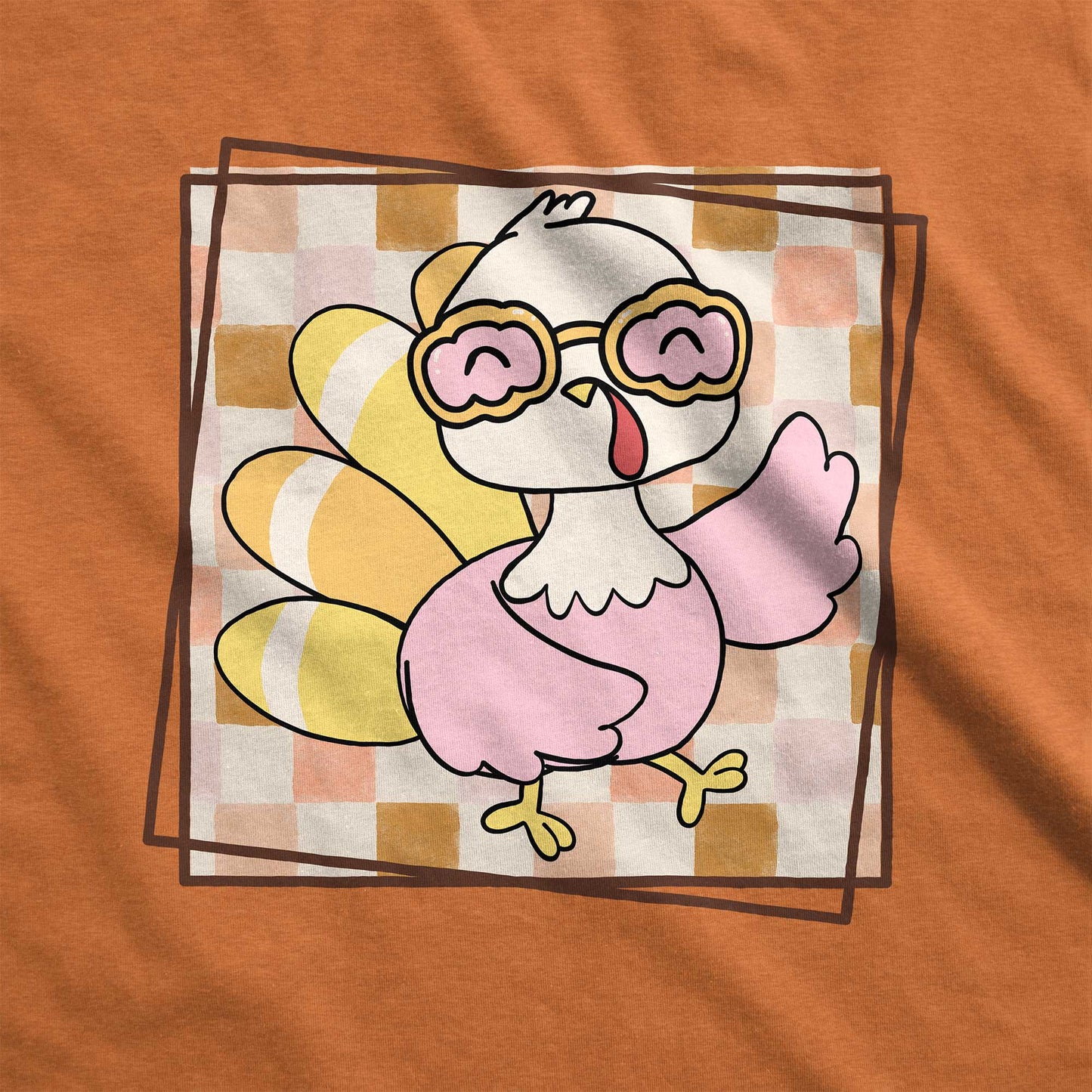 A heather autumn Bella Canvas swatch featuring a cute cartoon turkey against a fall checkered background.