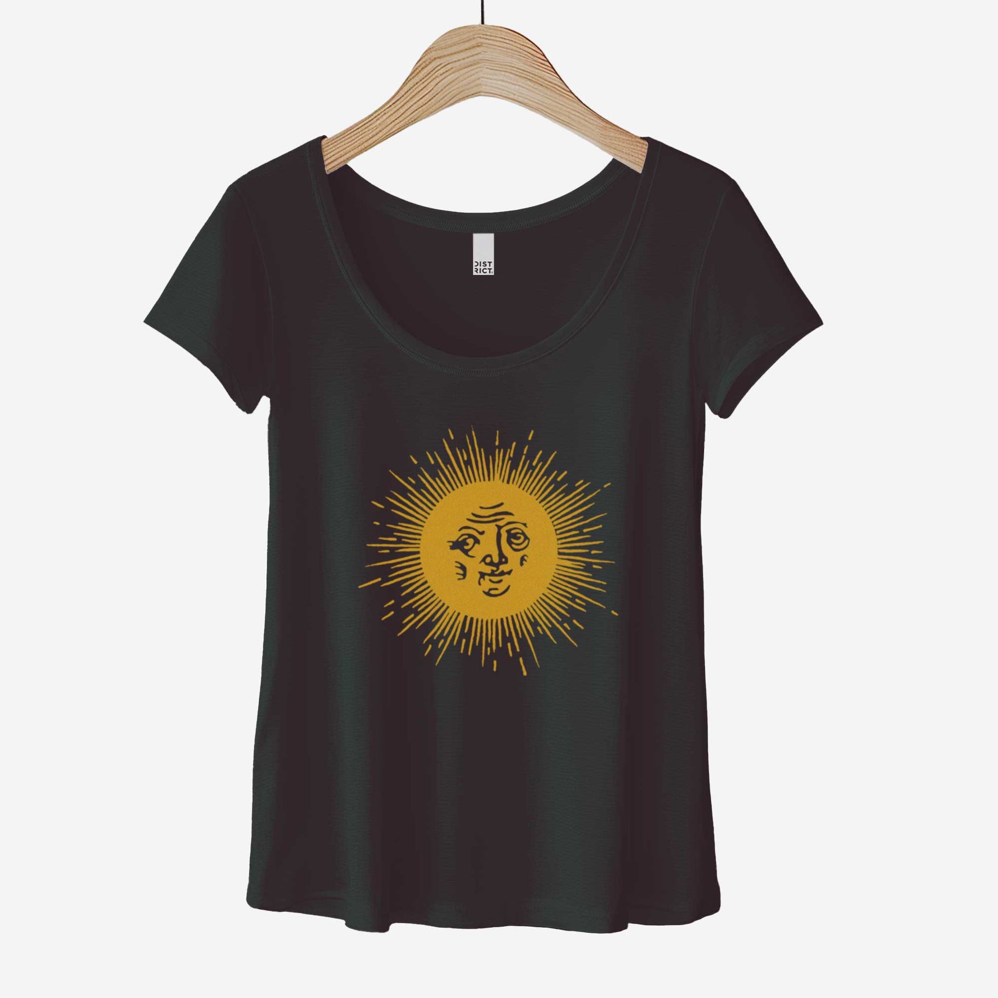 A hanging black District 7501 scoop neck t-shirt featuring a medieval woodcut illustration of the sun with a face inside.