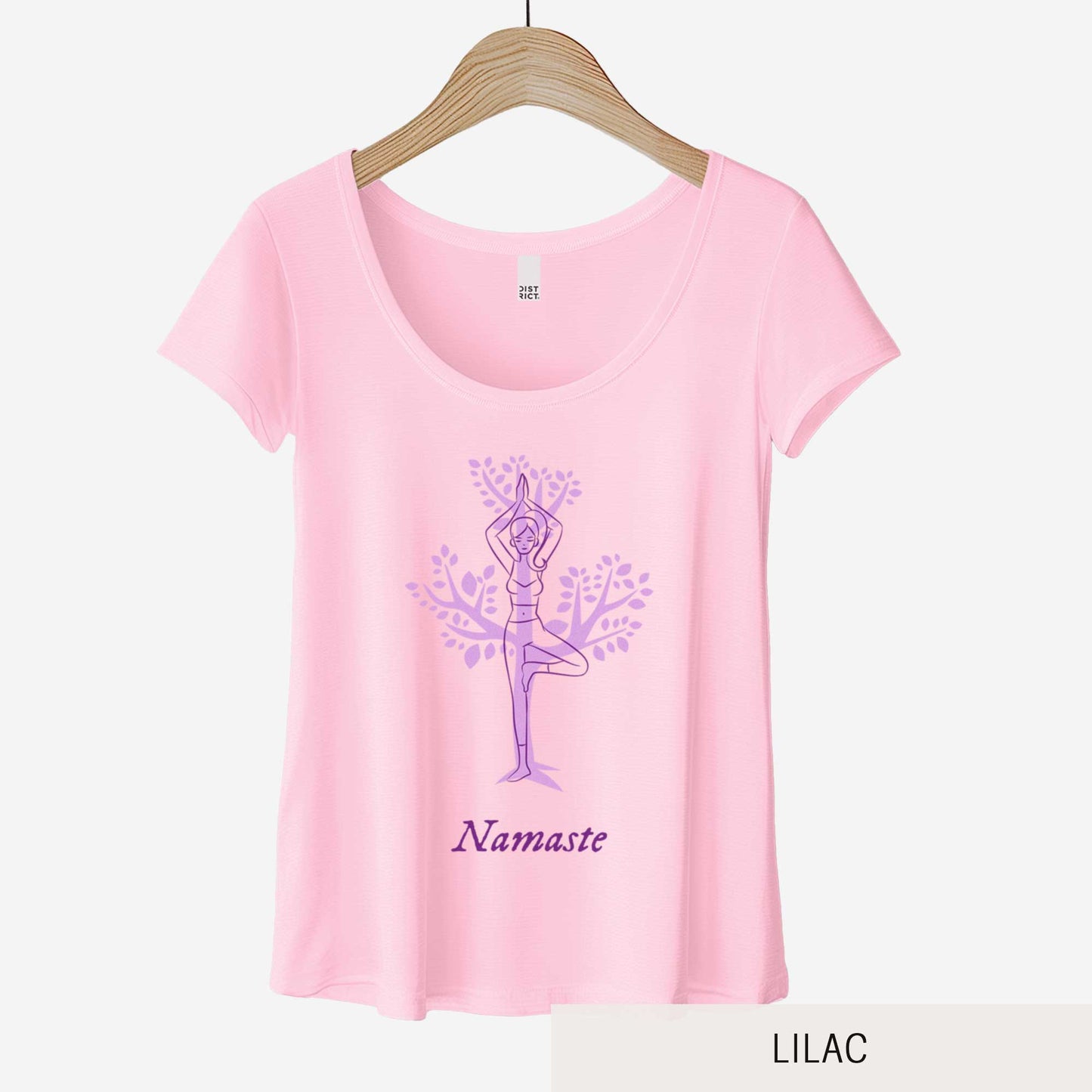 A hanging lilac District 7501 scoop neck t-shirt featuring a cartoon woman doing the tree pose in front of a tree silhouette and the words namaste below her.
