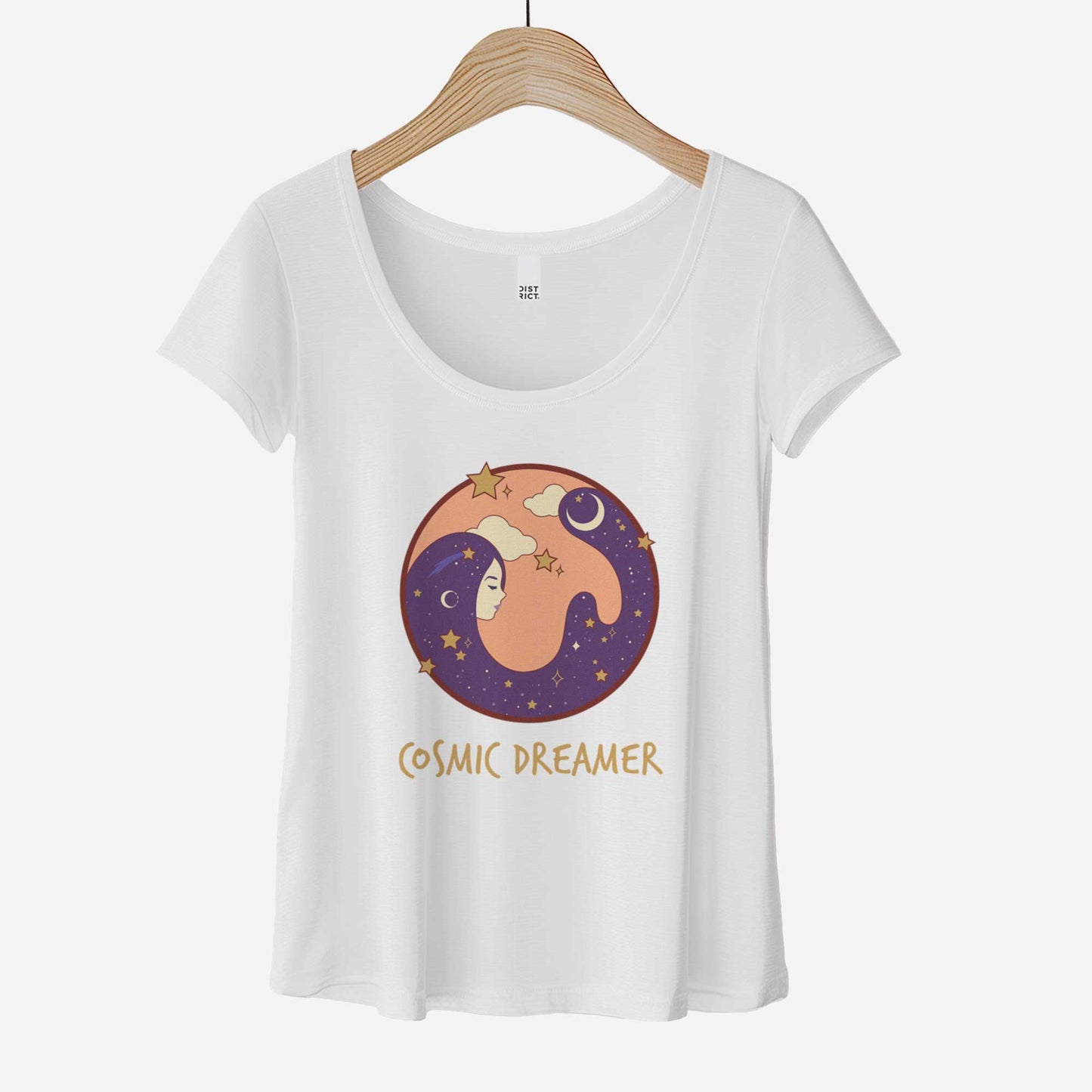 A hanging white District 7501 scoop neck t-shirt featuring a circle with a female face and hair that makes up the night sky and the words cosmic dreamer.