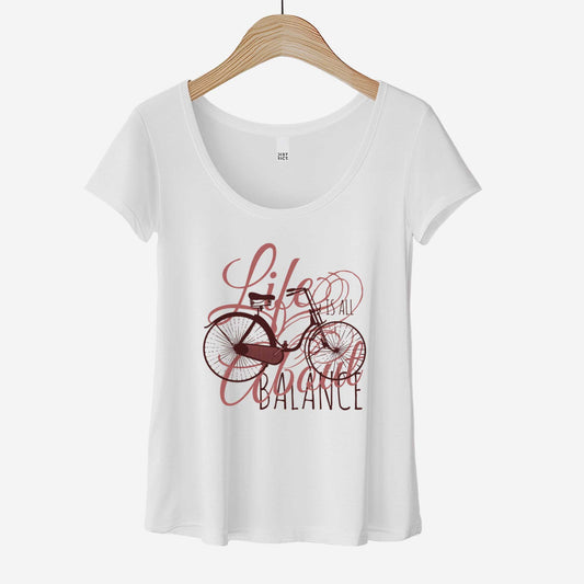 A hanging white District 7501 scoop neck t-shirt featuring a bicycle and the words life is all about balance.