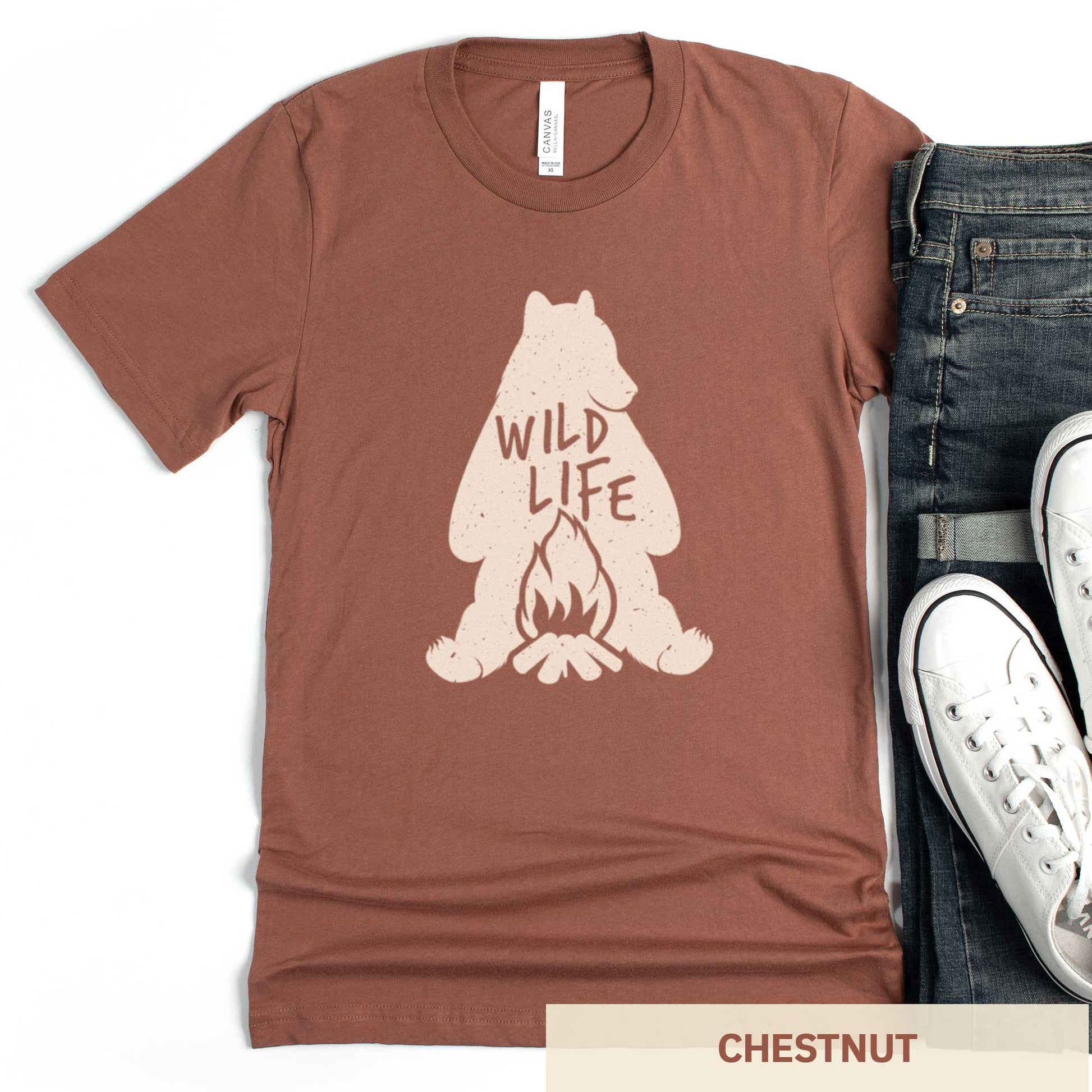 A chestnut cocoa brown Bella Canvas t-shirt featuring a silhouette of a grizzly bear sitting in front of a campfire with the words wild life.