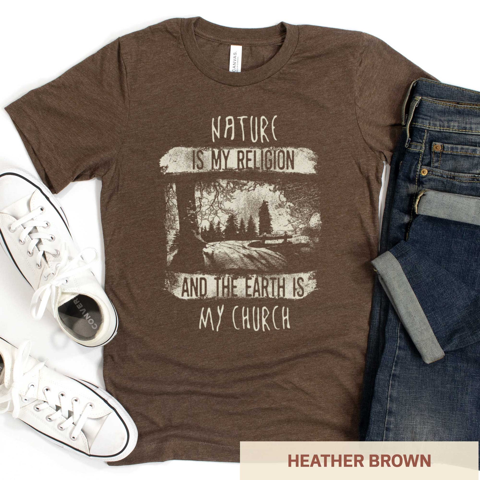 A heather brown Bella Canvas t-shirt featuring fields and a forest with the words nature is my religion and the earth is my church.