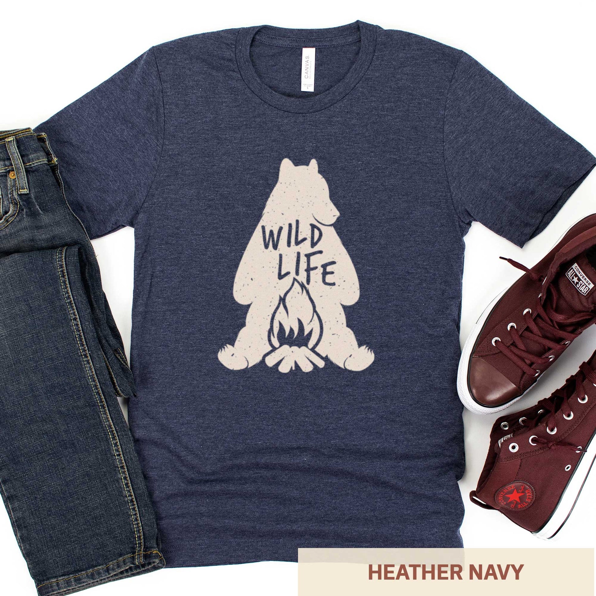 An heather navy Bella Canvas t-shirt featuring a silhouette of a grizzly bear sitting in front of a campfire with the words wild life.