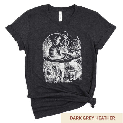 A dark grey heather Bella Canvas t-shirt featuring the John Tenniel illustration of Alice in Wonderland meeting the caterpillar who is sitting on a mushroom.