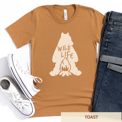 A toast brownish yellow Bella Canvas t-shirt featuring a silhouette of a grizzly bear sitting in front of a campfire with the words wild life.