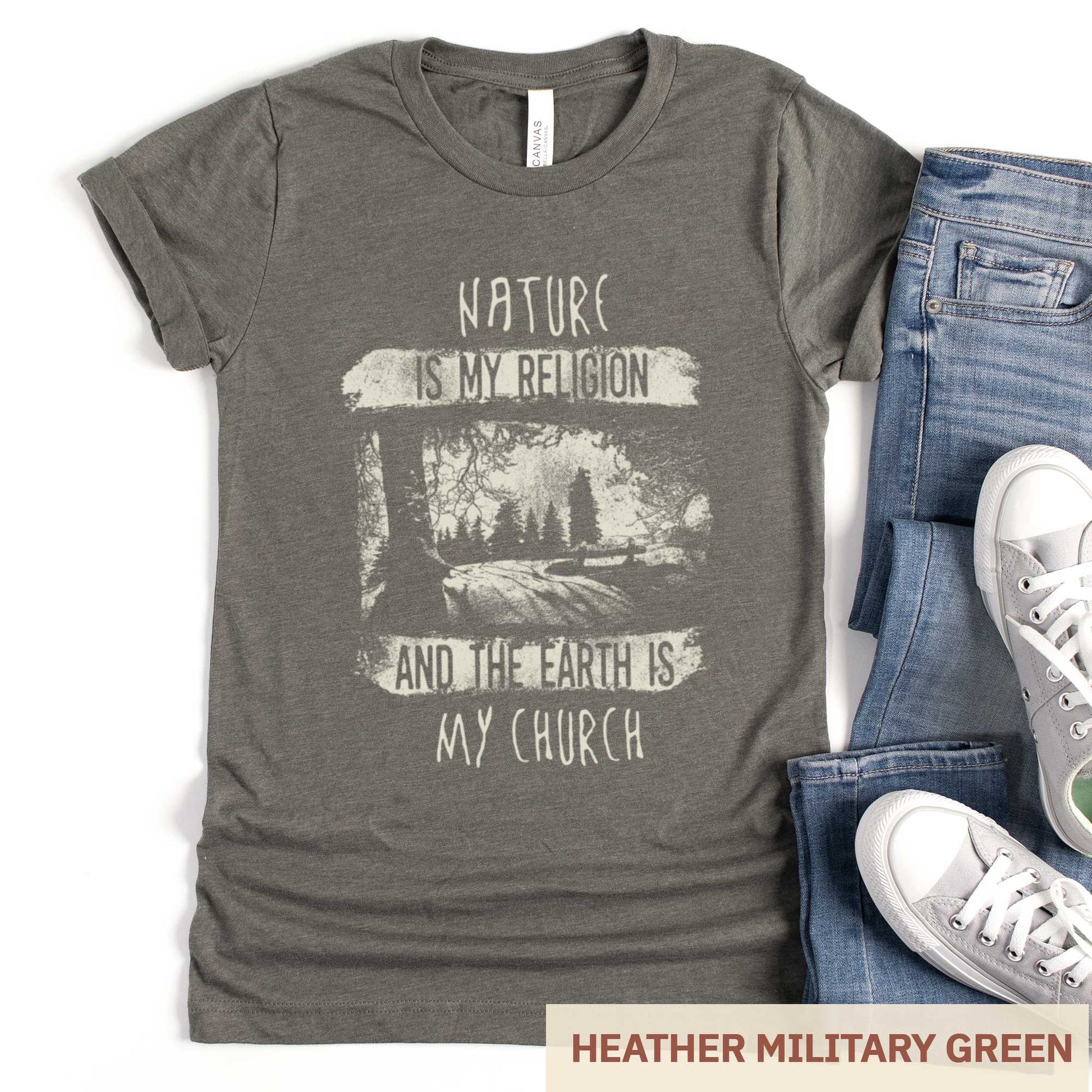A heather military green Bella Canvas t-shirt featuring fields and a forest with the words nature is my religion and the earth is my church.
