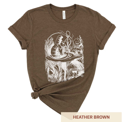 A heather brown Bella Canvas t-shirt featuring the John Tenniel illustration of Alice in Wonderland meeting the caterpillar who is sitting on a mushroom.
