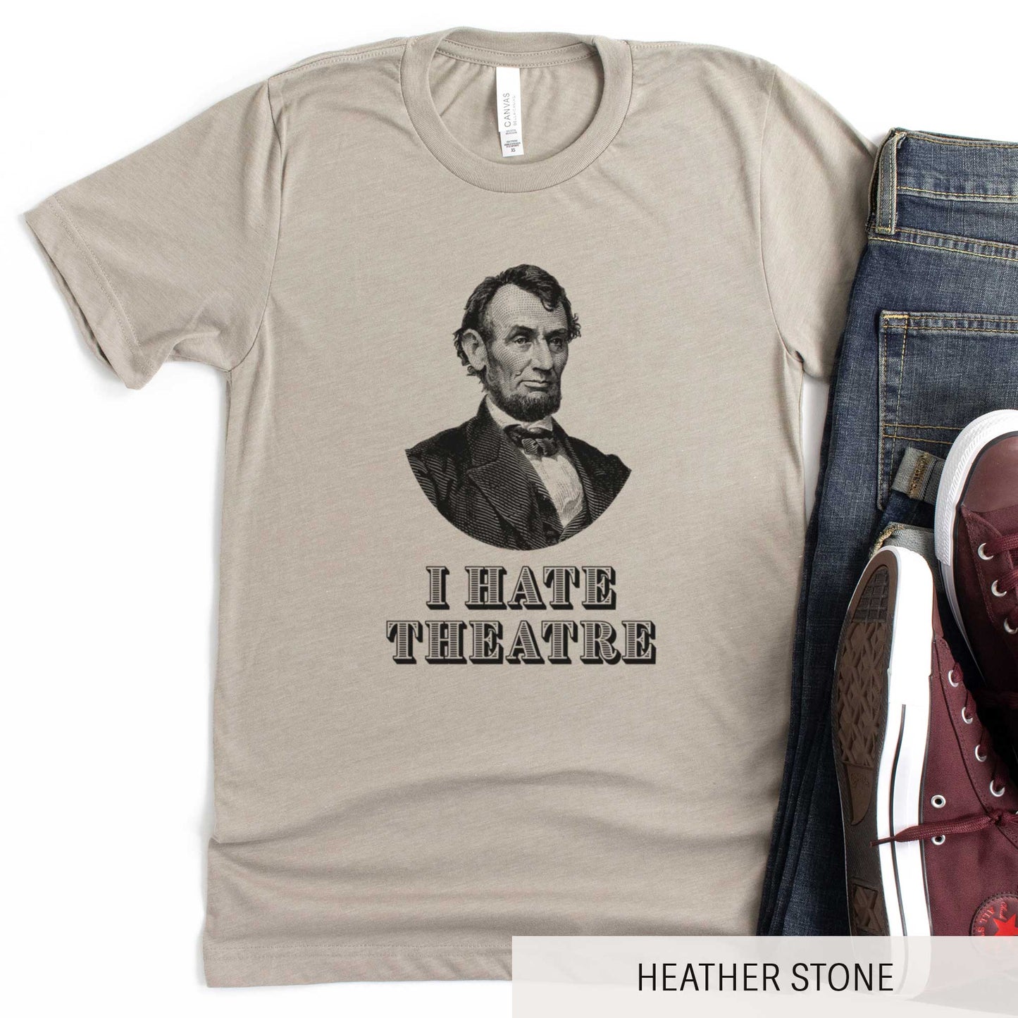 A heather stone Bella Canvas t-shirt featuring a vintage illustration of Abraham Lincoln with the words I hate theatre below it.