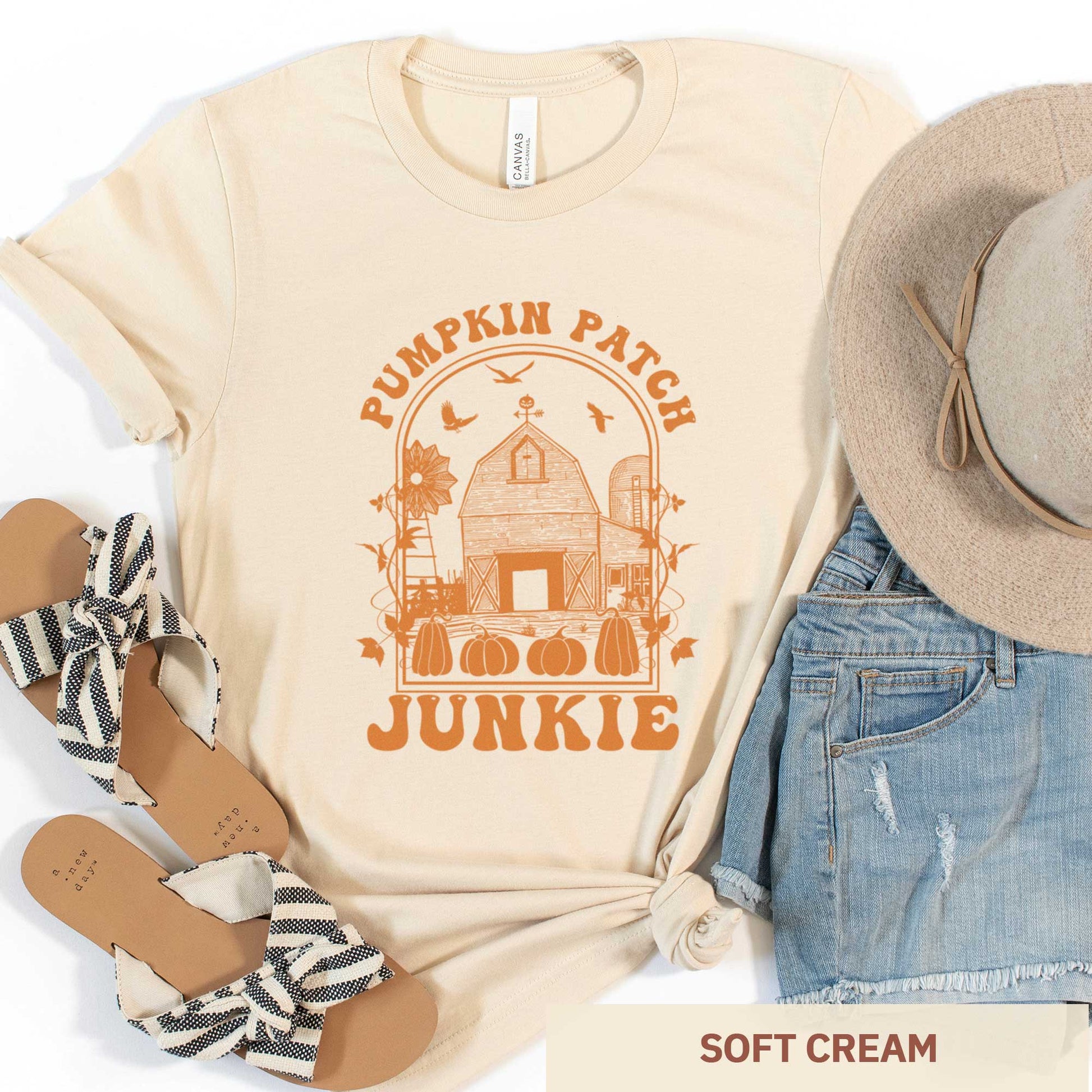 A soft cream Bella Canvas t-shirt featuring a farm with pumpkins that says pumpkin patch junkie.