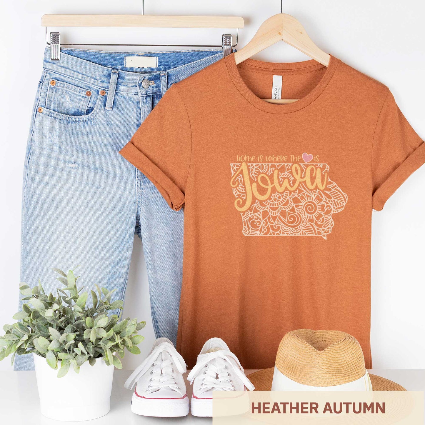 A hanging heather autumn Bella Canvas t-shirt featuring a mandala in the shape of Iowa with the words home is where the heart is.