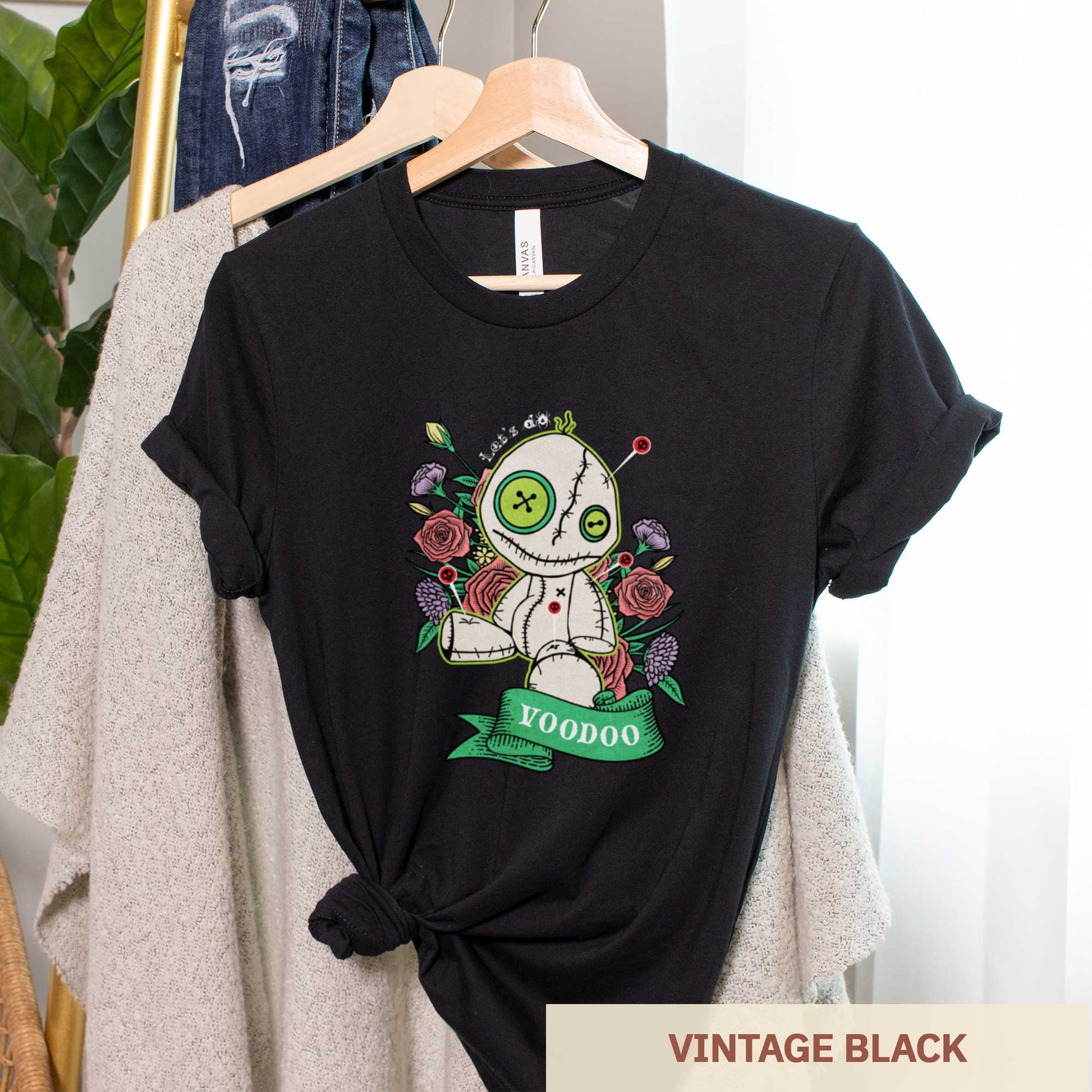 A vintage black heather Bella Canvas t-shirt featuring a cartoon voodoo doll and flowers.