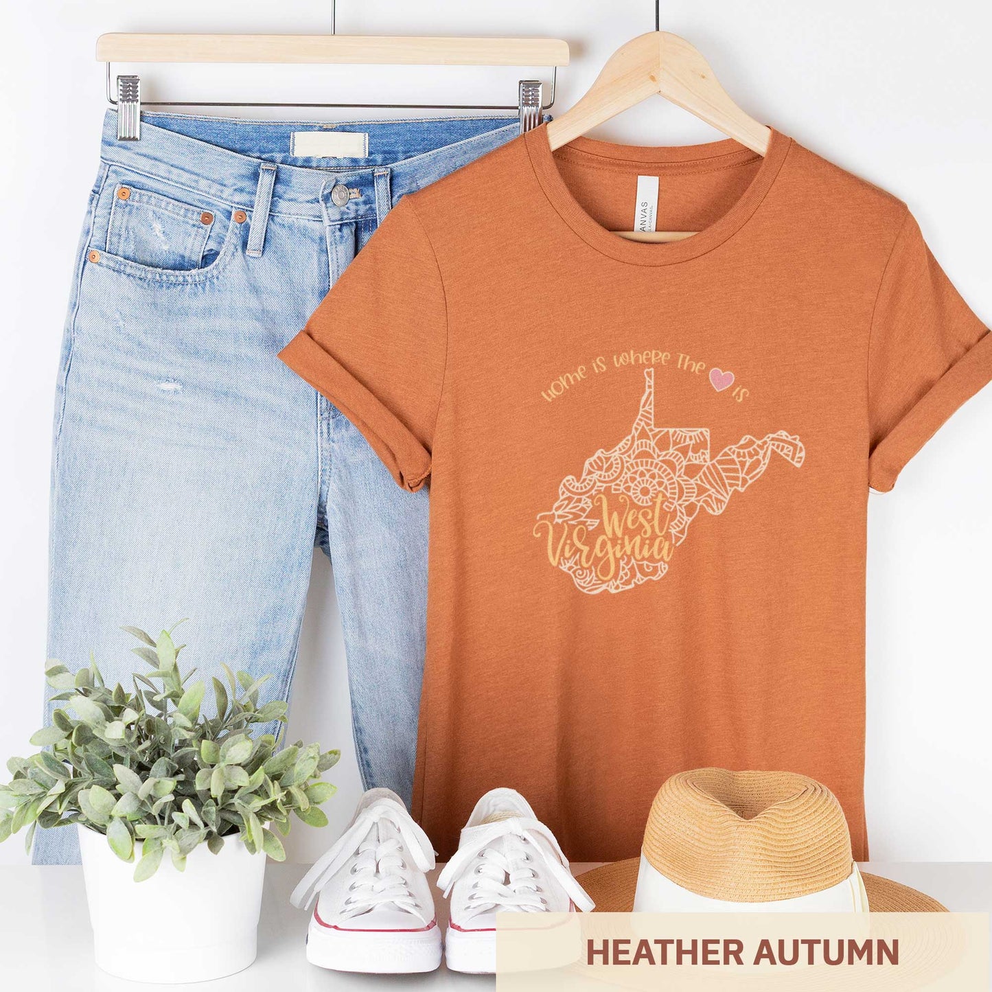 A hanging heather autumn Bella Canvas t-shirt featuring a mandala in the shape of West Virginia with the words home is where the heart is.