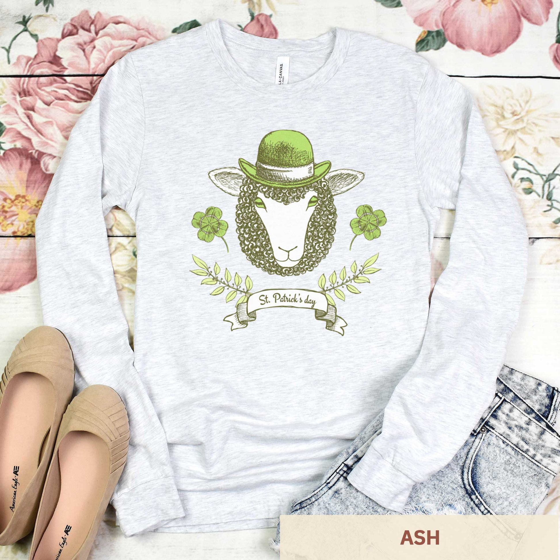A long sleeved ash Bella Canvas t-shirt featuring a sheep with a green hat, clovers and the words St.Patrick's Day.