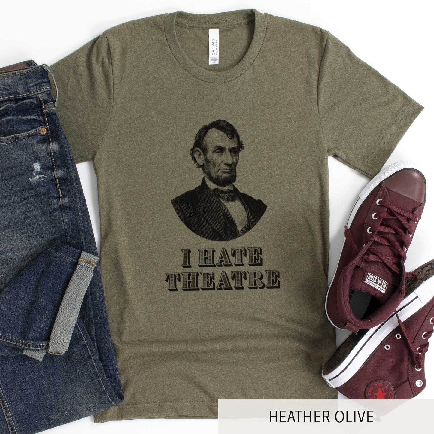 A heather olive Bella Canvas t-shirt featuring a vintage illustration of Abraham Lincoln with the words I hate theatre below it.