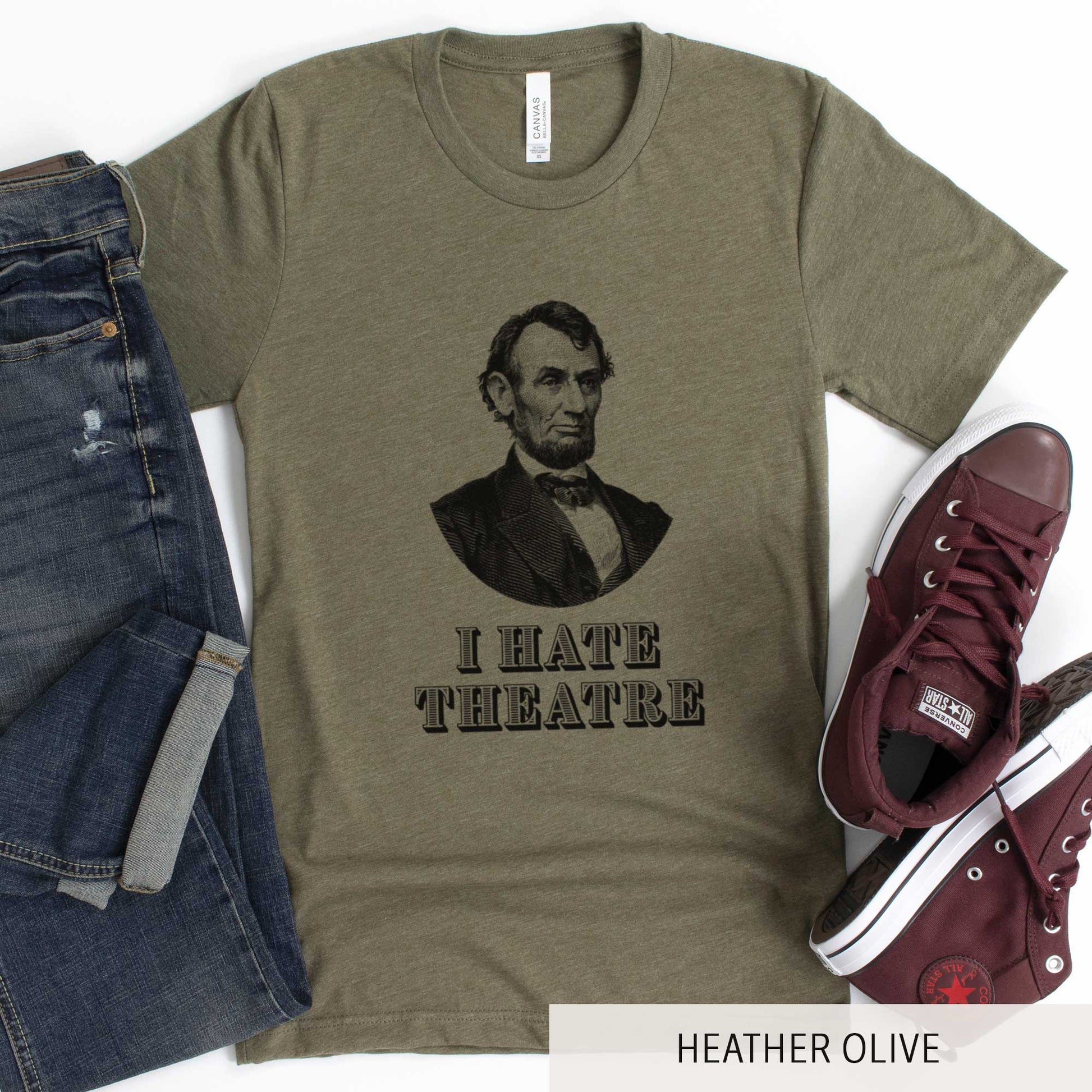 A heather olive Bella Canvas t-shirt featuring a vintage illustration of Abraham Lincoln with the words I hate theatre below it.