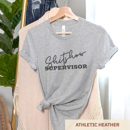 A hanging athletic heather Bella Canvas t-shirt featuring the text shitshow supervisor.
