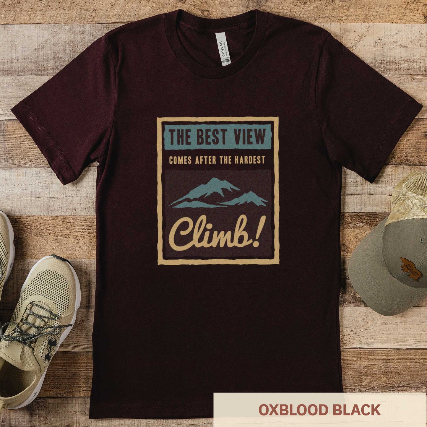 An oxblood black Bella Canvas t-shirt that features mountains and the words the best view comes after the hardest climb.