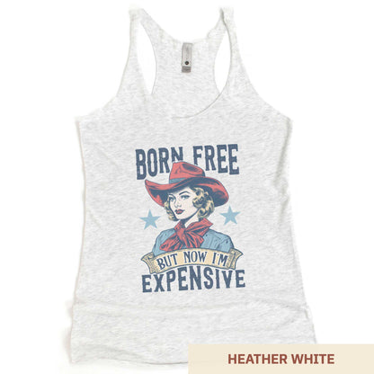 A heather white Next Level racerback tank featuring a retro cowgirl with the words born free but now i'm expensive.