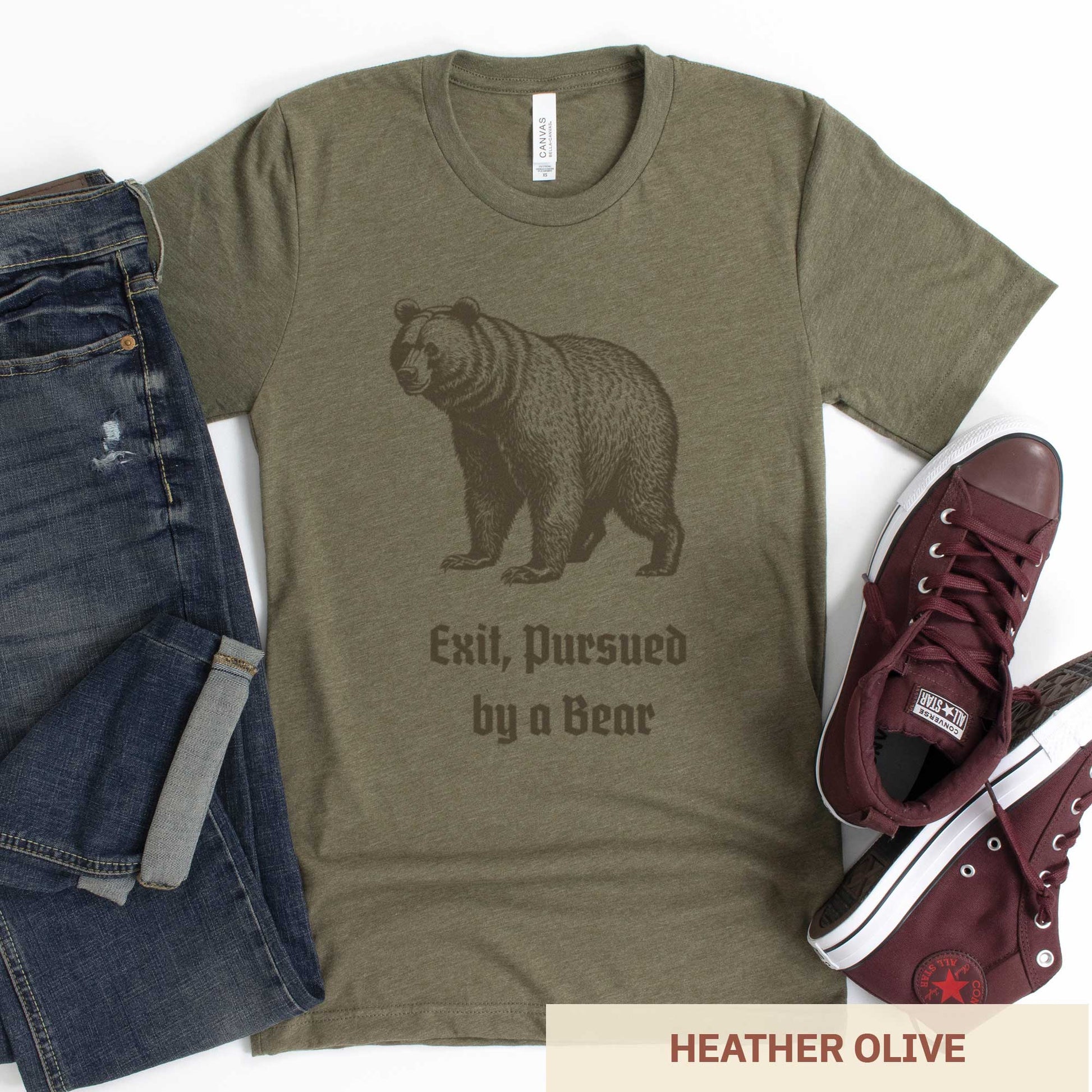 A heather olive Bella Canvas t-shirt featuring a vintage looking bear with the words exit, pursued by a bear.