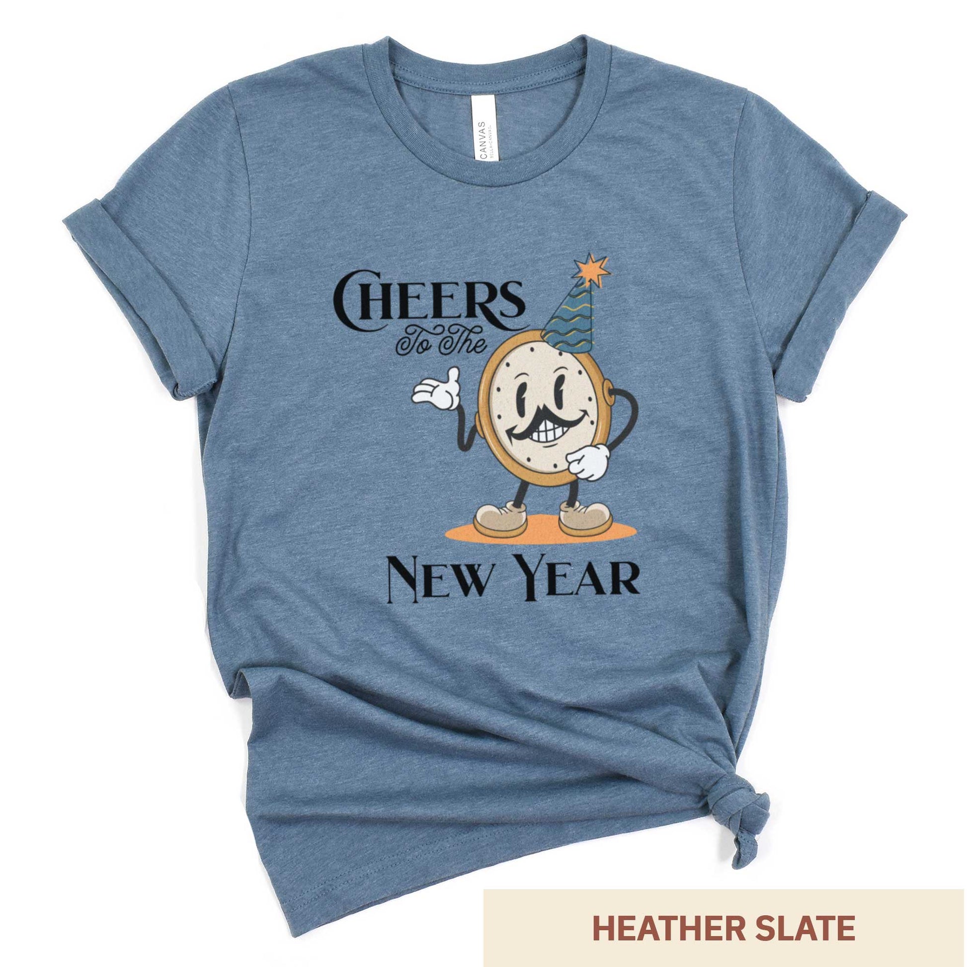 A heather slate Bella Canvas t-shirt featuring a retro looking clock cartoon with a party hat next to the words Cheers to the New Year.