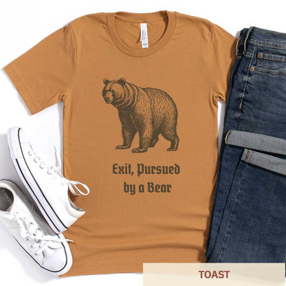 A toast orange-brown Bella Canvas t-shirt featuring a vintage looking bear with the words exit, pursued by a bear.