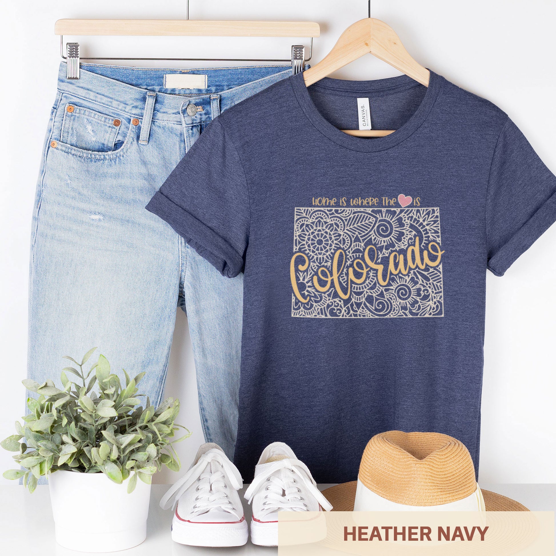  A hanging heather navy Bella Canvas t-shirt featuring a mandala in the shape of Colorado with the words home is where the heart is.