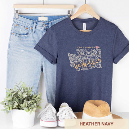 A hanging heather navy Bella Canvas t-shirt featuring a mandala in the shape of Washington with the words home is where the heart is.