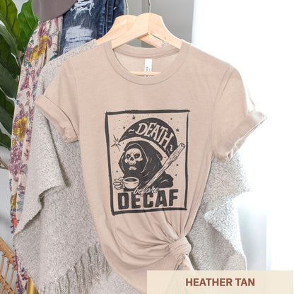A hanging heather tan Bella Canvas t-shirt featuring the grim reaper drinking a cup of coffee with the words Death before decaf