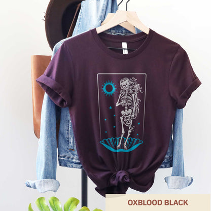 A hanging oxblood black Bella Canvas t-shirt that features a skeleton in a pose similar to Botticelli's Birth of Venus painting.