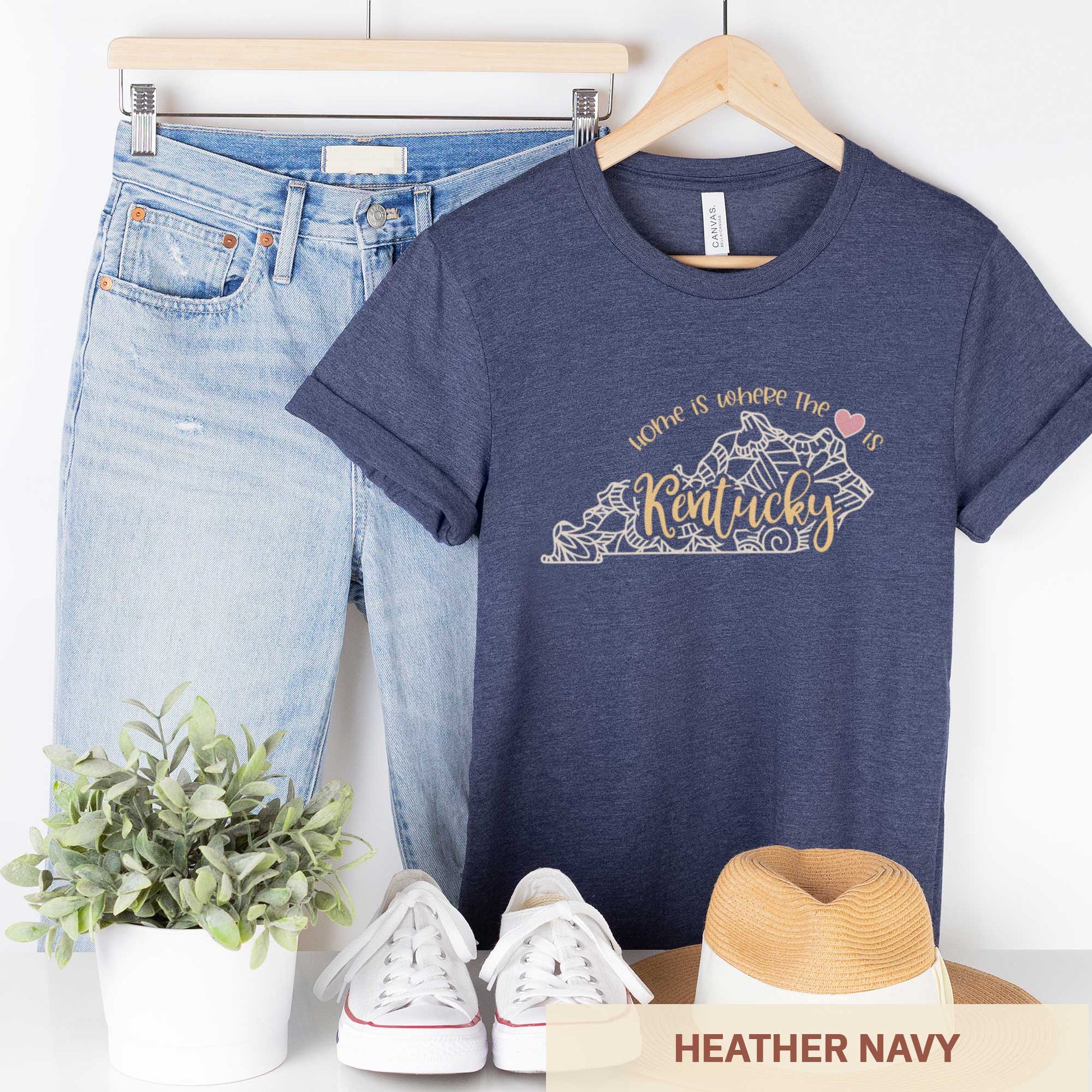A hanging heather navy Bella Canvas t-shirt featuring a mandala in the shape of Kentucky with the words home is where the heart is.