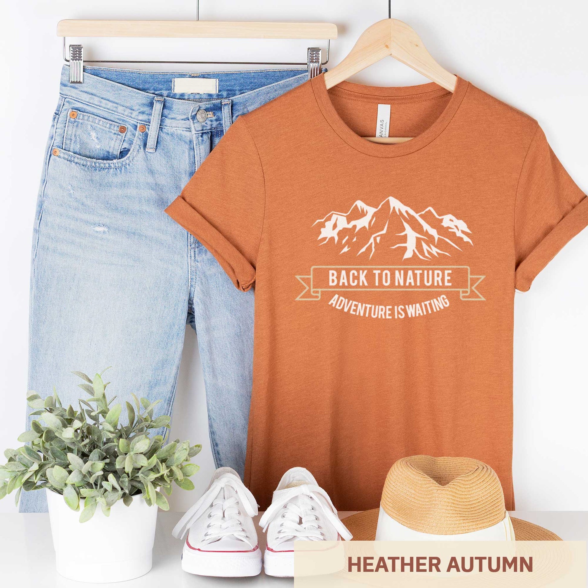 A hanging heather autumn Bella Canvas t-shirt that says back to nature with mountains.