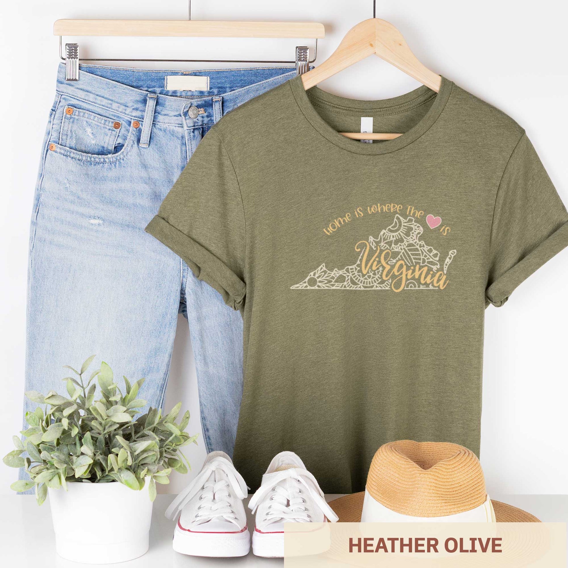 A hanging heather olive Bella Canvas t-shirt featuring a mandala in the shape of Virginia with the words home is where the heart is.