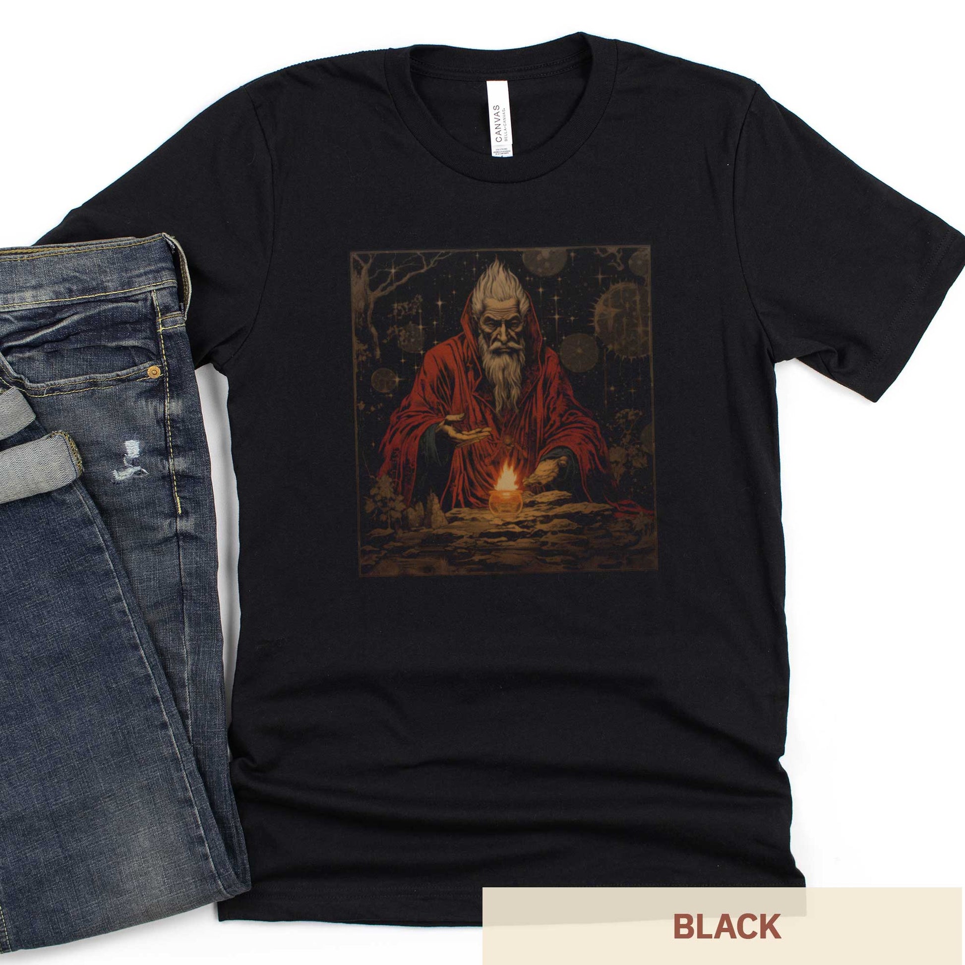 A black Bella Canvas t-shirt featuring a medieval looking sourcerer casting a spell over a small open flame.