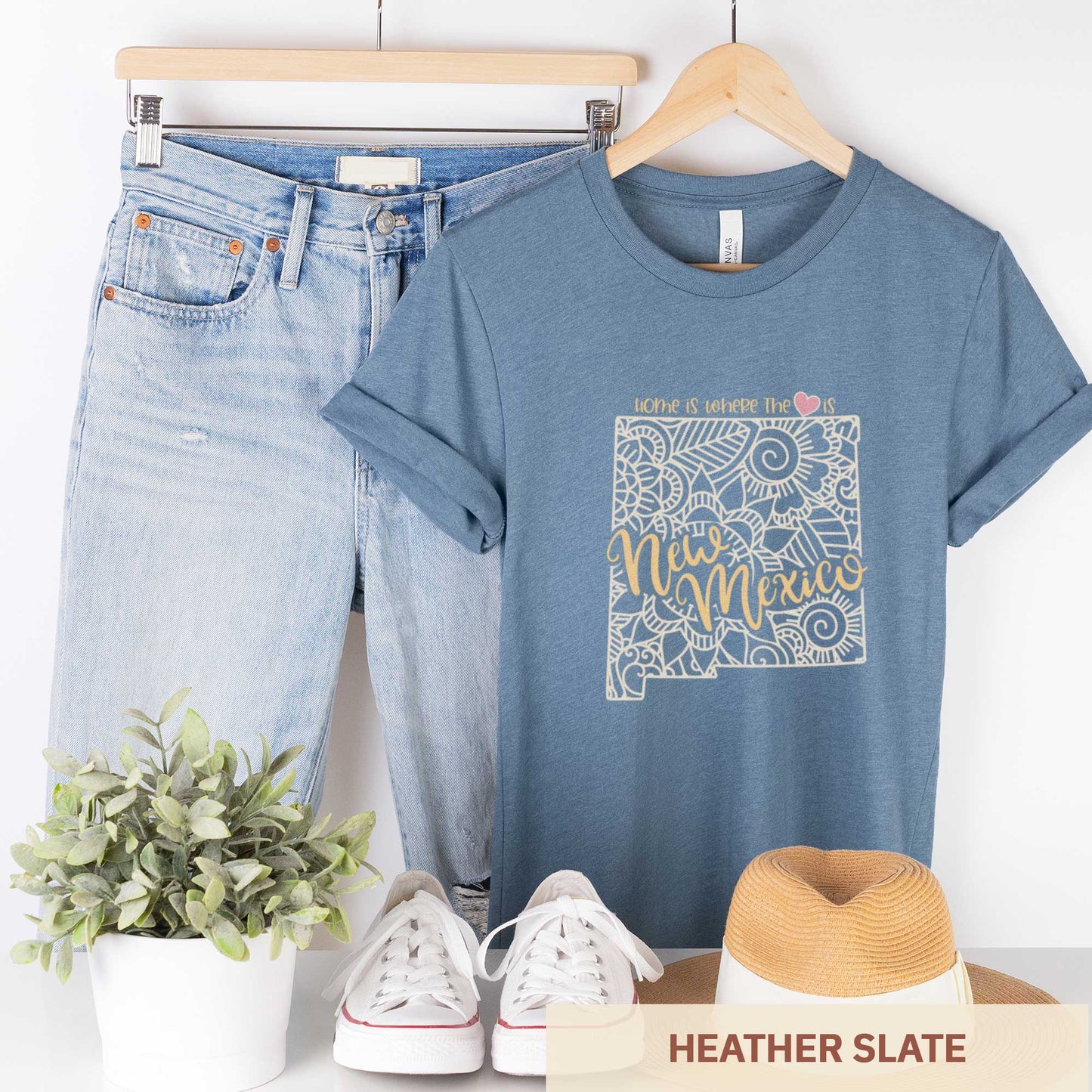 A hanging heather slate Bella Canvas t-shirt featuring a mandala in the shape of New Mexico with the words home is where the heart is.