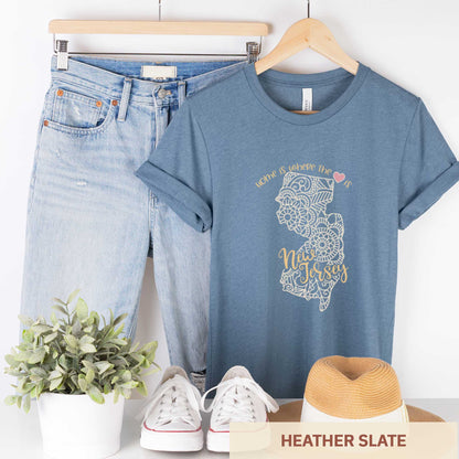 A hanging heather slate Bella Canvas t-shirt featuring a mandala in the shape of New Jersey with the words home is where the heart is.