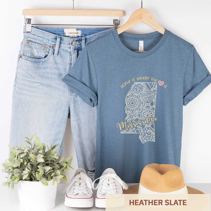 A hanging heather slate Bella Canvas t-shirt featuring a mandala in the shape of Mississippi with the words home is where the heart is.