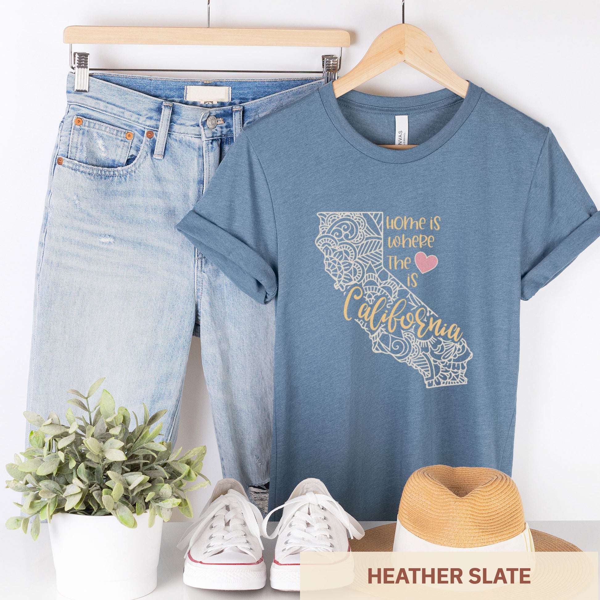 A hanging heather slate Bella Canvas t-shirt featuring a mandala in the shape of California with the words home is where the heart is.