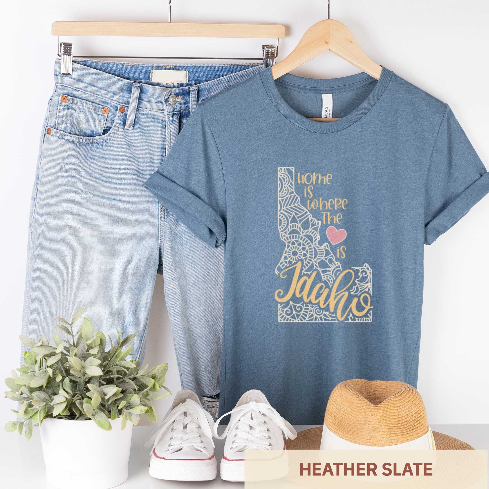 A hanging heather slate Bella Canvas t-shirt featuring a mandala in the shape of Idaho with the words home is where the heart is.