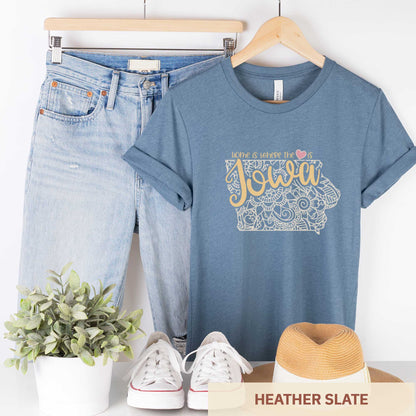 A hanging heather slate Bella Canvas t-shirt featuring a mandala in the shape of Iowa with the words home is where the heart is.