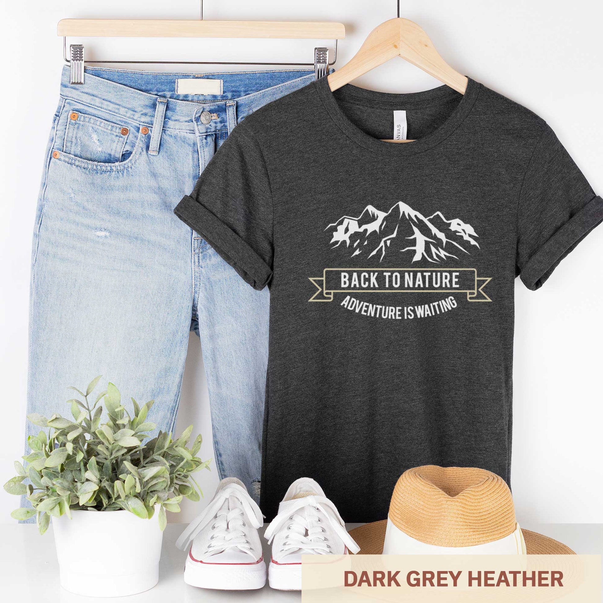 A hanging dark grey heather Bella Canvas t-shirt that says back to nature with mountains.
