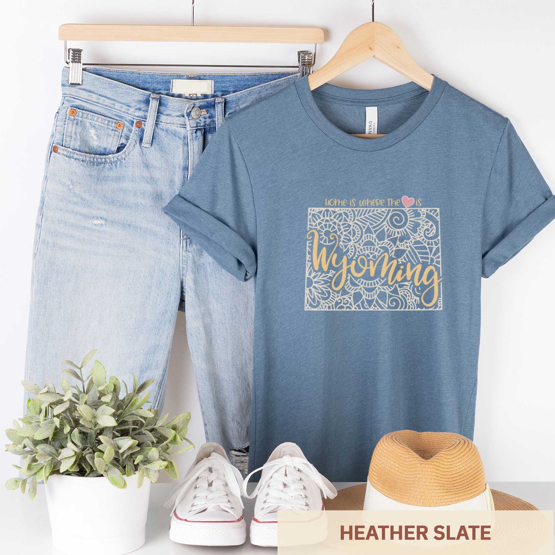 A hanging heather slate Bella Canvas t-shirt featuring a mandala in the shape of Wyoming with the words home is where the heart is.