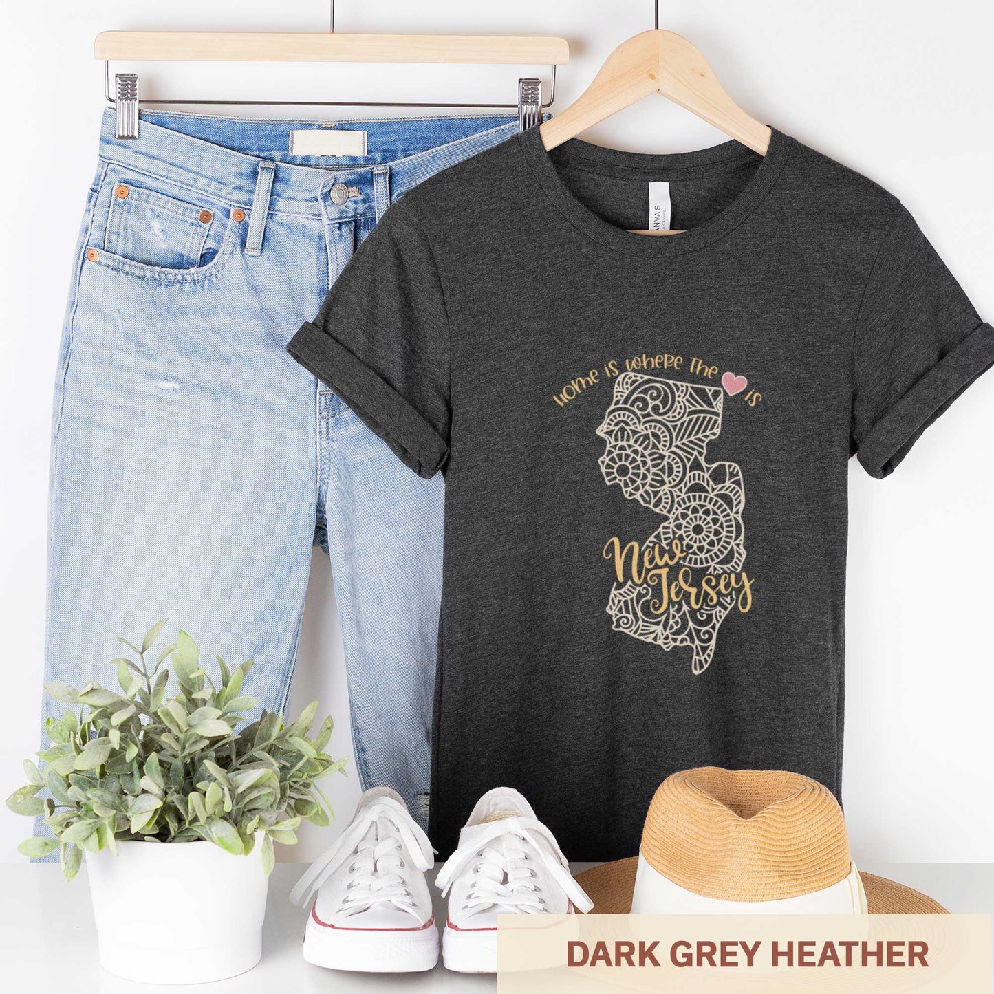 A hanging dark grey heather Bella Canvas t-shirt featuring a mandala in the shape of New Jersey with the words home is where the heart is.
