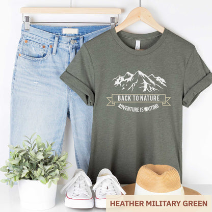 A hanging heather military green Bella Canvas t-shirt that says back to nature with mountains.