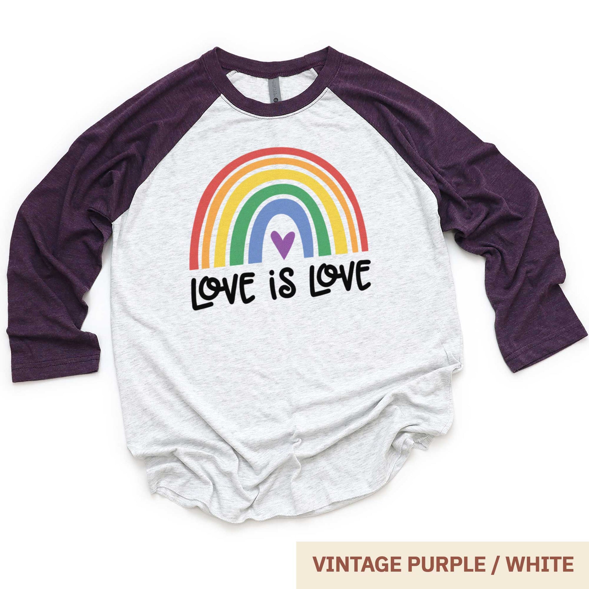 A vintage purple and heather white Next Level raglan swatch featuring a multi-colored rainbow with the words love is love below it.