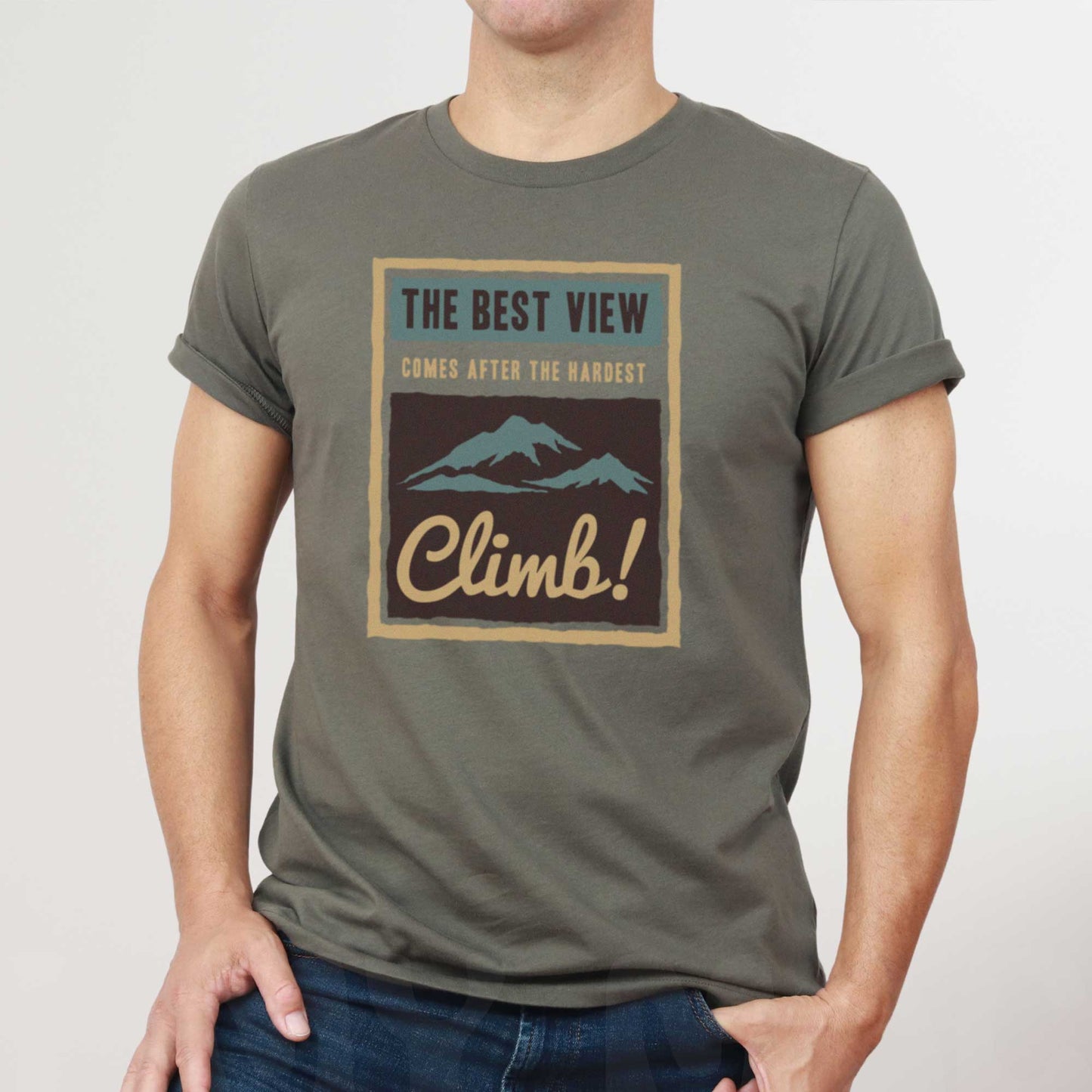 A man wearing an army green Bella Canvas t-shirt that features mountains and the words the best view comes after the hardest climb.