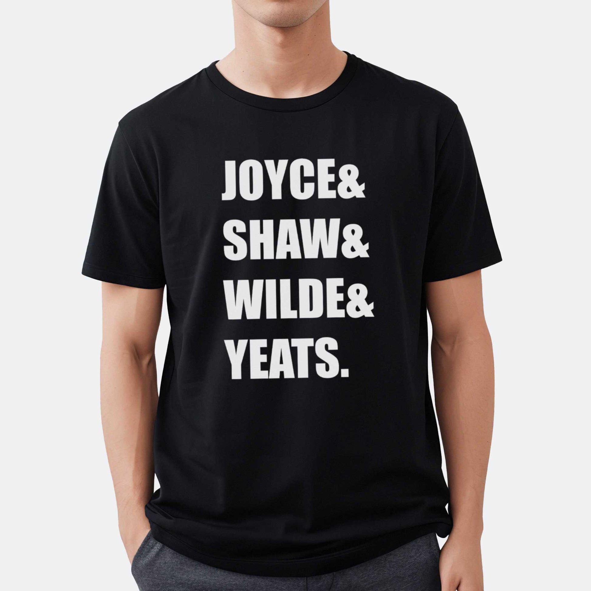 A man wearing a black Bella Canvas t-shirt featuring the last names of Irish writers Joyce, Shaw, Wilde and Yeats.