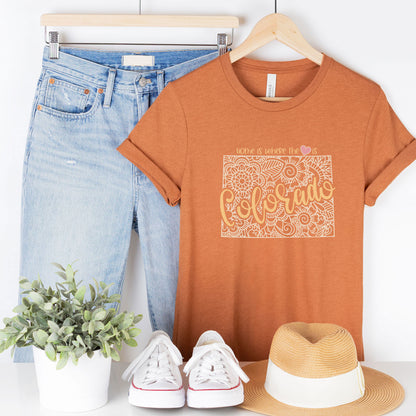  A hanging heather autumn Bella Canvas t-shirt featuring a mandala in the shape of Colorado with the words home is where the heart is.